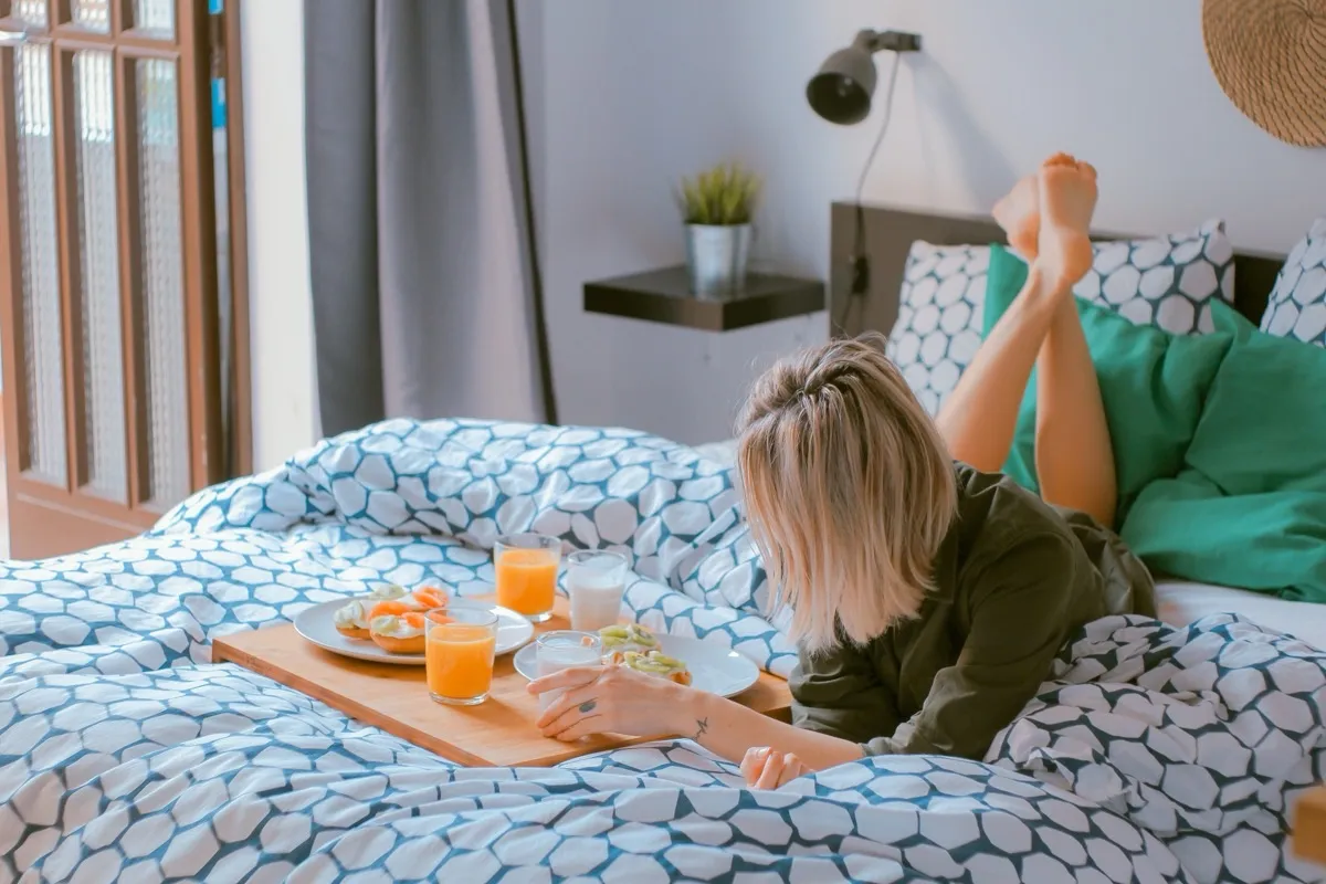 Cama vestida con edredón azul y una bandeja de desayuno servida encima