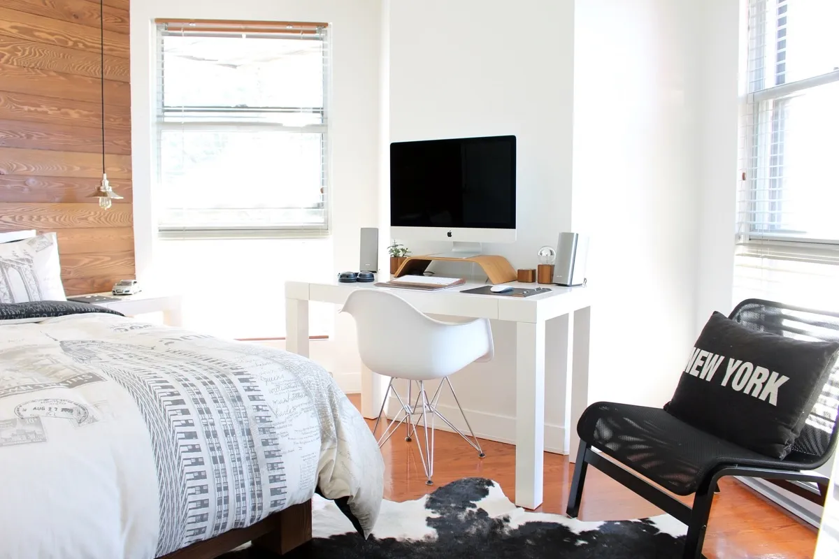 Habitación con cama doble, pared de madera y escritorio junto a la ventana