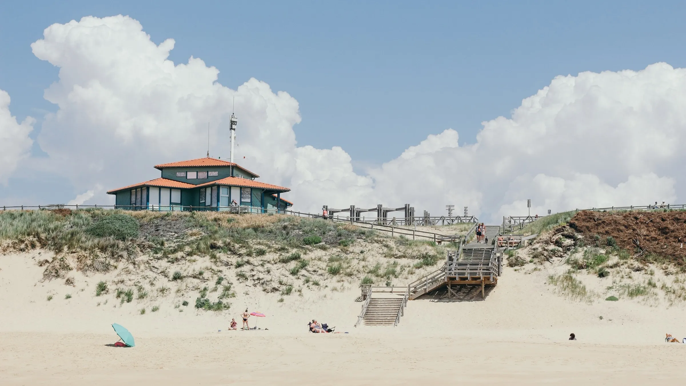 La casa de madera sobre las dunas, con la playa y el mar en primer plano